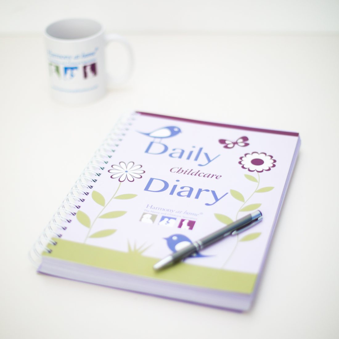 The Daily Childcare Nanny Diary with a pen and mug