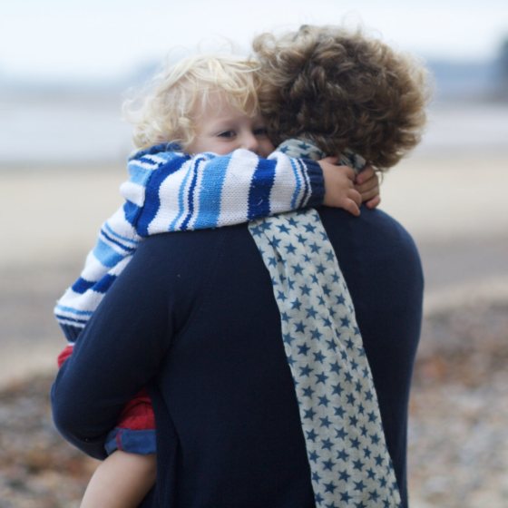 A toddler hugging Frankie on the beach